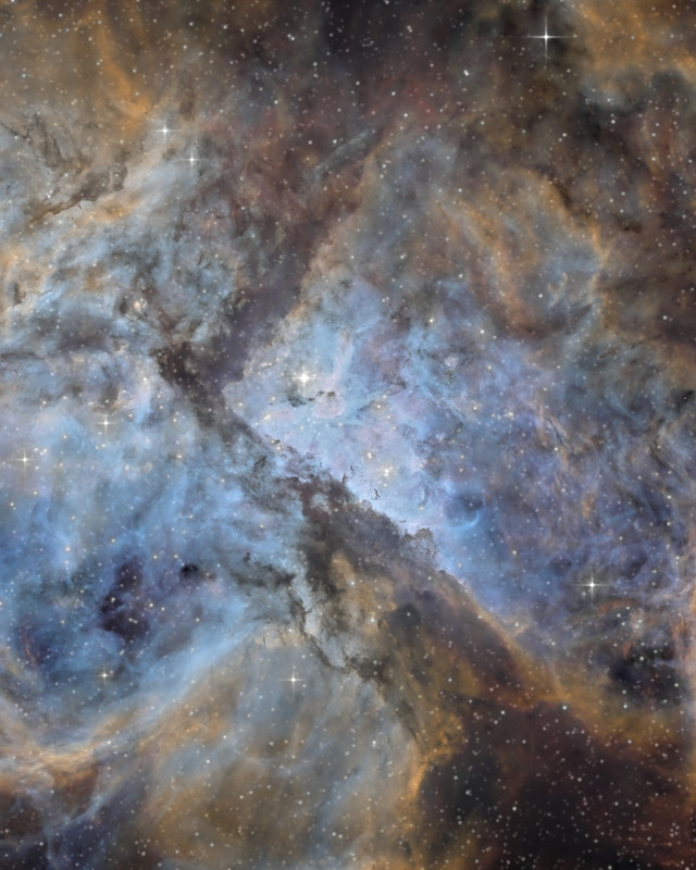 青白く光るガスの中のイータ・カリーナと、斜めに走る暗いちりの帯 / Eta Carinae in pale blue glowing gas, with dark lanes of dust running diagonally