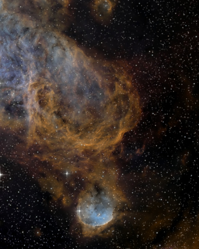 銅色のガスの殻の下にある、縁の明るい丸い星雲NGC 3324 / The round, bright-rimmed nebula NGC 3324 below shells of copper-coloured gas
